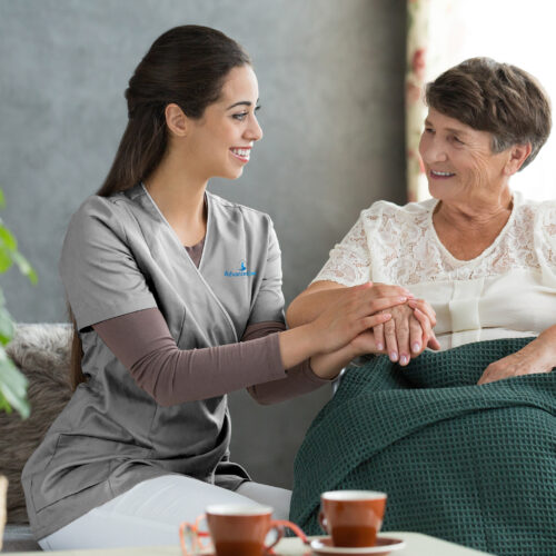Carer kneeling beside an elderly patient. Patient is sitting on a wheelchair.